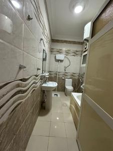 uma casa de banho com um lavatório, um WC e um lavatório. em الفخامة الجنوبية للشقق المخدومة em Jazan
