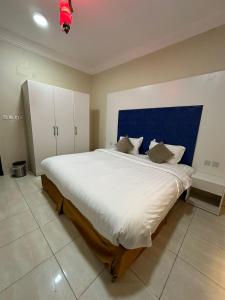 1 dormitorio con 1 cama grande y cabecero azul en الفخامة الجنوبية للشقق المخدومة en Jazán