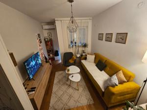 ein Wohnzimmer mit einem gelben Sofa und einem TV in der Unterkunft Apartman U2 in Veliko Gradište