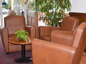uma sala de espera com cadeiras castanhas e uma mesa com uma planta em ibis Albert Pays de Somme em Albert