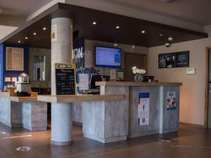 a restaurant with a counter in a room at Ibis Budget Archamps Porte de Genève in Archamps