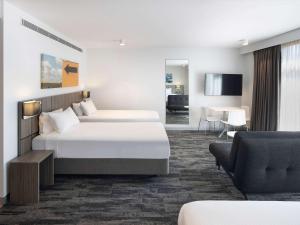 um quarto de hotel com duas camas e uma sala de estar em Mercure Sydney Blacktown em Blacktown