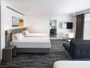 a hotel room with two beds and a living room at Mercure Sydney Blacktown in Blacktown