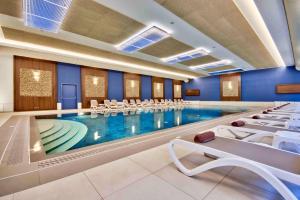 a large swimming pool with white chairs in a building at DoubleTree by Hilton Malta in St Paul's Bay