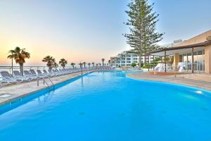 a large swimming pool with chairs and a resort at DoubleTree by Hilton Malta in St Paul's Bay