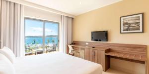 a hotel room with a bed and a tv and a window at DoubleTree by Hilton Malta in St Paul's Bay