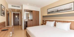 a bedroom with a large white bed and a desk at DoubleTree by Hilton Malta in St Paul's Bay
