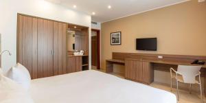 a bedroom with a bed and a desk with a television at DoubleTree by Hilton Malta in St Paul's Bay