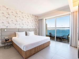 a bedroom with a bed and a view of the ocean at DoubleTree by Hilton Malta in St Paul's Bay