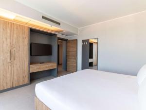 a bedroom with a white bed and a television at DoubleTree by Hilton Malta in St Paul's Bay