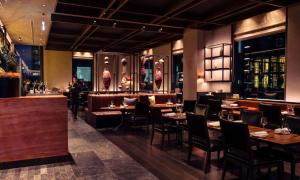 a restaurant with tables and chairs and a bar at Next Hotel Melbourne, Curio Collection by Hilton in Melbourne