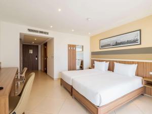 a bedroom with a large white bed and a desk at DoubleTree by Hilton Malta in St Paul's Bay