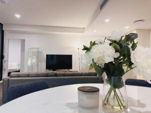 un vase de fleurs blanches sur une table dans le salon dans l'établissement Cityscape Oasis Homes at Toowong Precinct, à Brisbane