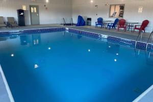 Una gran piscina azul con sillas y una mesa. en Baymont by Wyndham Danville IL, en Danville