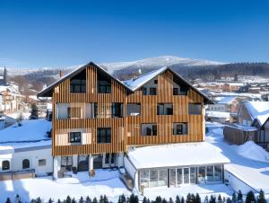 een houten huis bovenop met sneeuw bedekte gebouwen bij Das Kronberg - Adults Only Hotel in Bodenmais