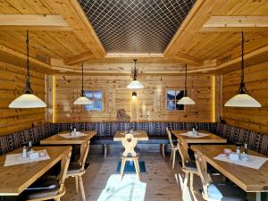 um restaurante com mesas e cadeiras de madeira e luzes pendentes em Berghotel Almrausch em Berwang