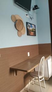 a table with two chairs and a hat on a wall at Hotel Vitoria Andradina in Andradina