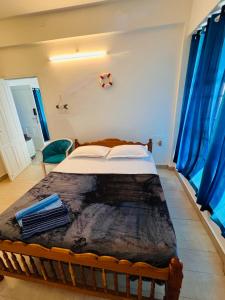 Ocean View في كولام: غرفة نوم بسرير كبير مع ستائر زرقاء