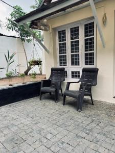 dwa czarne krzesła siedzące przed domem w obiekcie Ocean View w mieście Kollam