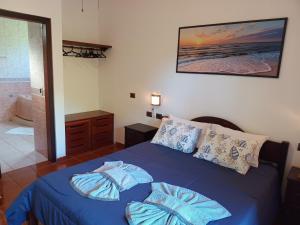a bedroom with a blue bed and a bathroom at Solar das Canoas Prumirim in Ubatuba