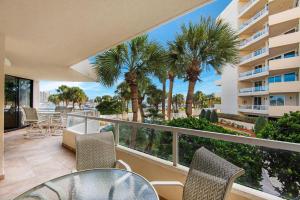 a balcony with tables and chairs and palm trees at East Pass 102 in Destin