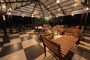un patio al aire libre con mesas y sillas y un techo en StayVista's Orange Theory - Pet-Friendly Villa with Outdoor Pool, Lawn featuring a Gazebo, en Rāipur