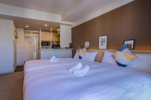 a bedroom with a large white bed with towels on it at Apartment Hotel 11 Shinsaibashi III in Osaka