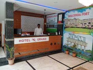 a man standing at the counter of a hotel x grand restaurant at HOTEL NEW MN GRAND in Hyderabad