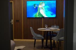 a dining room with a table and a tv on a wall at Elexus Apartments Poiana Brasov in Poiana Brasov