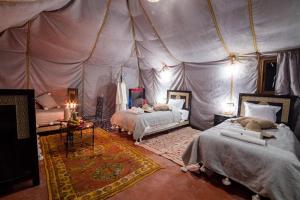 um quarto com 2 camas numa tenda em Best Desert luxury camp em Merzouga
