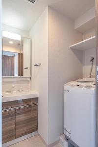 a bathroom with a sink and a mirror and a refrigerator at Apartment Hotel 11 Shinsaibashi III in Osaka