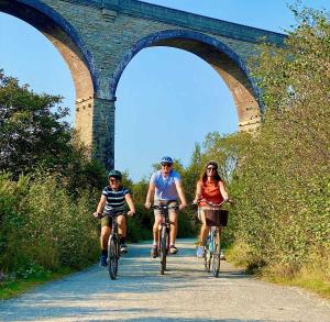 3 persone che cavalcano le biciclette lungo una strada sotto un ponte di Feock beautiful sunny cottage a Truro