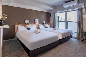 2 Betten in einem Hotelzimmer mit einem großen Fenster in der Unterkunft Apartment Hotel 11 Shinsaibashi III in Osaka