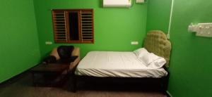 a small green room with a bed and a window at Siddharth illam in Puducherry