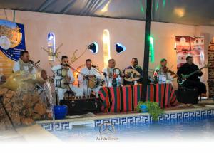 un groupe d'hommes jouant aux instruments à côté d'un pool dans l'établissement La Villa Tezribt, à Ghardaïa