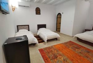 a room with three beds and a tv in it at La Villa Tezribt in Rhardaïa