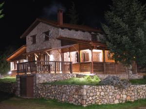 a house with a stone wall in front of it at Mont Valley Boutique Chalets in Arachova