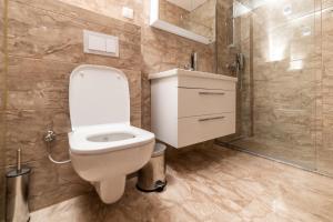 a bathroom with a white toilet and a shower at Emery Apartments in Prishtinë