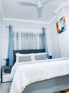 a bedroom with a large white bed with blue curtains at Pelican Apartment in Durban