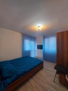 um quarto com uma cama azul e cortinas azuis em Casă centru em Craiova