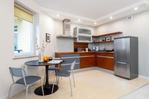 kuchnia ze stołem, krzesłami i lodówką w obiekcie Apartament Lothus - parking podziemny gratis, ścisłe centrum - by Kairos Apartments w mieście Gliwice