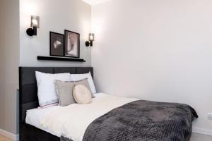 sypialnia z czarno-białym łóżkiem z poduszkami w obiekcie Apartament Lothus - parking podziemny gratis, ścisłe centrum - by Kairos Apartments w mieście Gliwice