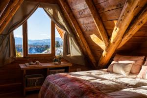1 dormitorio con 1 cama y 1 mesa con ventana en Pueblo Alto Lodge en Lago Futalaufquen