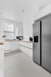 a white kitchen with a stainless steel refrigerator at Luxury 3 bedroom apartment in the heart of High Street Kensington, London. in London