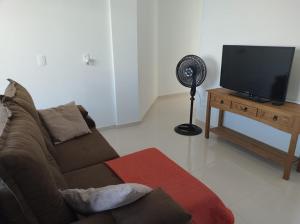 Il comprend un salon doté d'un canapé, d'une télévision et d'un ventilateur. dans l'établissement Apartamento Novo 500m da praia de Itajuba, à Barra Velha