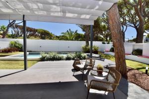 un patio al aire libre con sillas y sombrilla en Villa Cactae, en Novo Sancti Petri