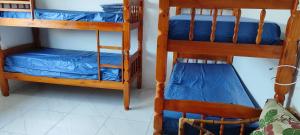 two bunk beds with blue sheets and a chair at Casa Praia Itanhaém - Avenida Santos in Itanhaém