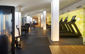 une salle de sport avec une rangée de tapis de course et de chaises dans l'établissement Hilton Garden Inn Frankfurt Airport, à Francfort-sur-le-Main