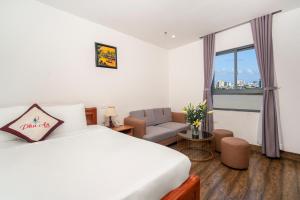 una camera da letto con un letto, un divano e una finestra di Phú An Hotel a Da Nang
