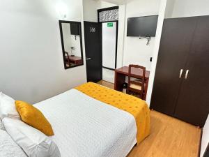 een slaapkamer met een bed, een kast en een televisie bij Hostal Habitaciones de la 39 in Pasto